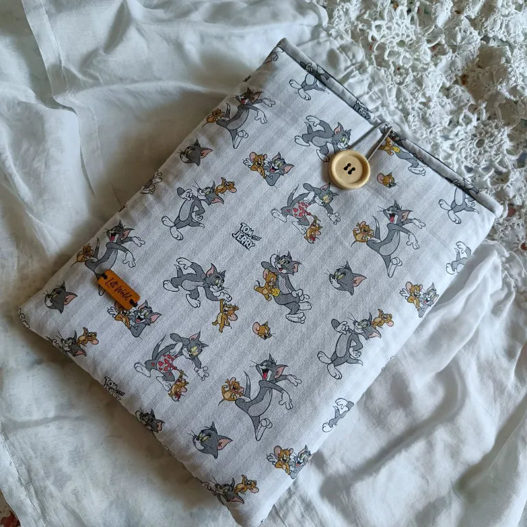 Funda para libro con ilustraciones de Tom y Jerry sobre fondo blanco, vista frontal