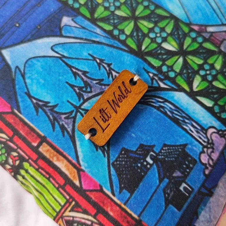 Primer plano enfocado en la pequeña chapa decorativa de la marca Lilt World cosida en la funda protectora de libros.