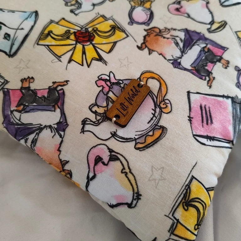 Primer plano enfocado sobre la ilustración de la tetera en la tela y la pequeña chapa de madera con la marca Lilt World.
