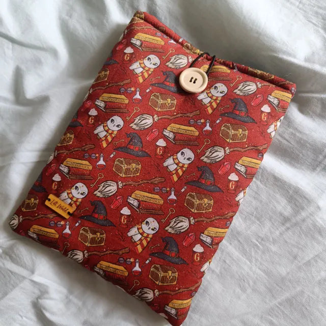 Accesorio de lectura con símbolos de Hogwarts, lechuzas, varitas y escobas.