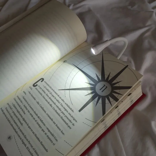 Lámpara de lectura recargable con luz ajustable sobre libro abierto - Ideal para leer en la cama