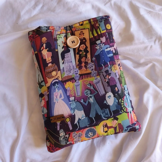 Vista principal de una funda acolchada de Mansión Encantada con estampado colorido de monstruos clásicos y botón de madera.