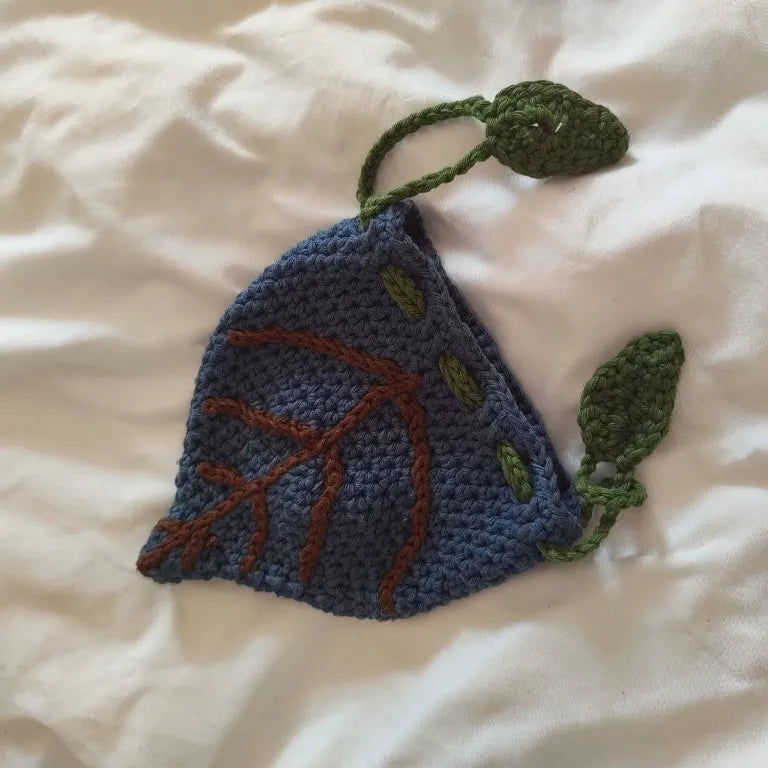 Primer plano de la bolsa para dados azul místico mostrando las nervaduras de hoja bordadas en marrón y el cierre de cordón con hojas.