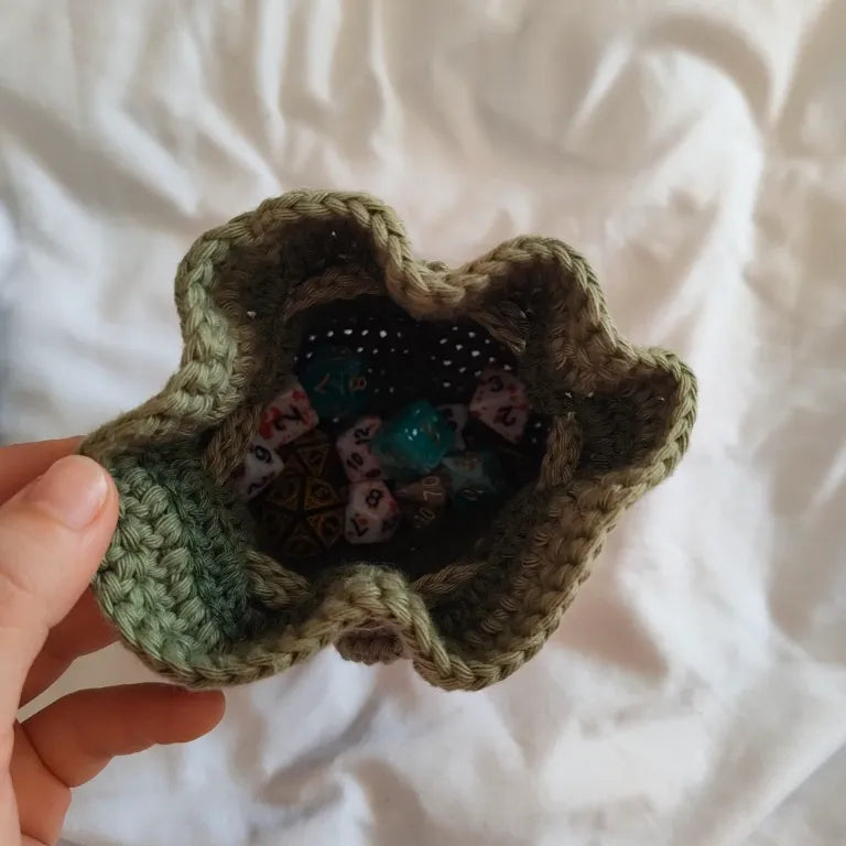Vista superior de la bolsa de dados verde abierta, mostrando una gran cantidad de dados poliédricos para D&D en su interior.