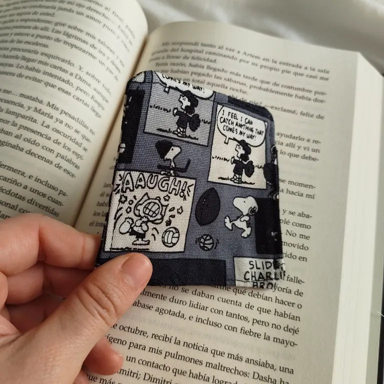 Primer plano de los dos modelos de marcapáginas de tela y la funda de libro a juego con estampado de Peanuts.