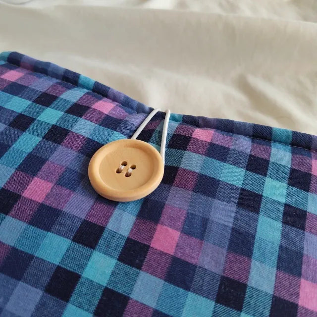 Primer plano del cierre de botón de madera en la funda de tela azul Ender.