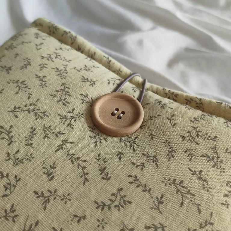 Detalle de cerca del sistema de cierre con botón de madera natural y cordón elástico en la funda Jane.