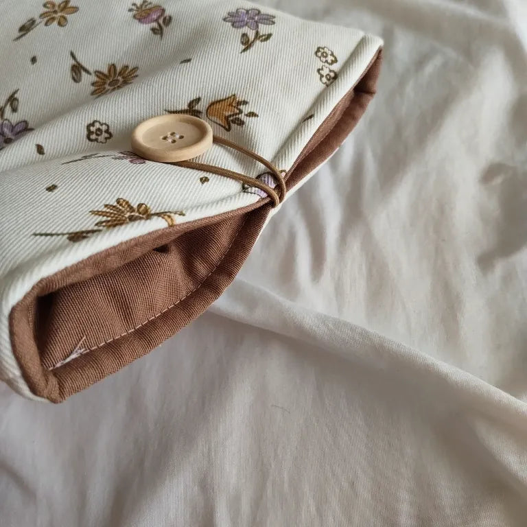 Detalle del interior acolchado marrón y el cierre de botón de madera de la funda Nora.