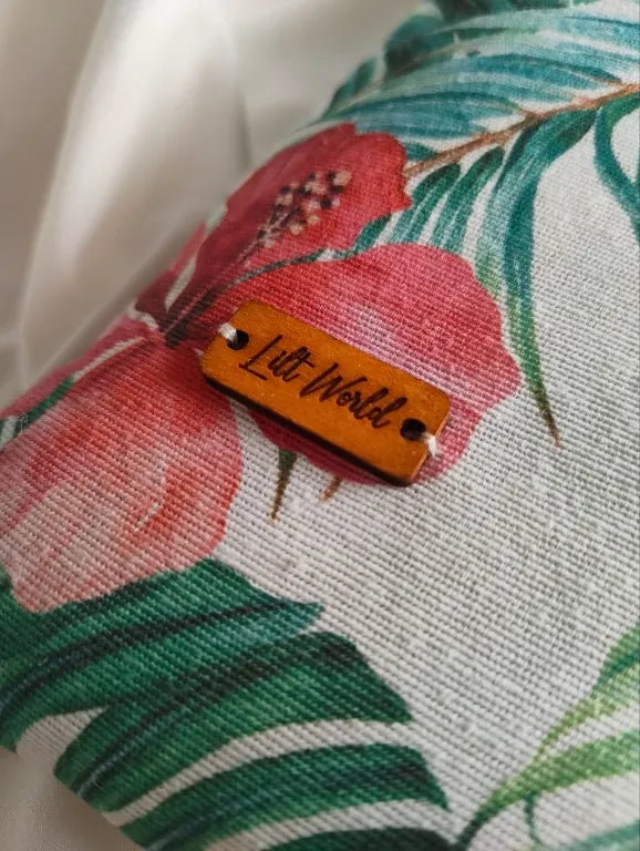 Primer plano de etiqueta de madera con logo Lilt World en funda de tela con estampado floral tropical de hibisco.