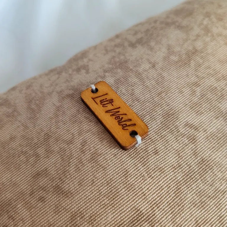 Primer plano de la chapa de madera de Lilt World sobre la tela de camuflaje en tonos arena.