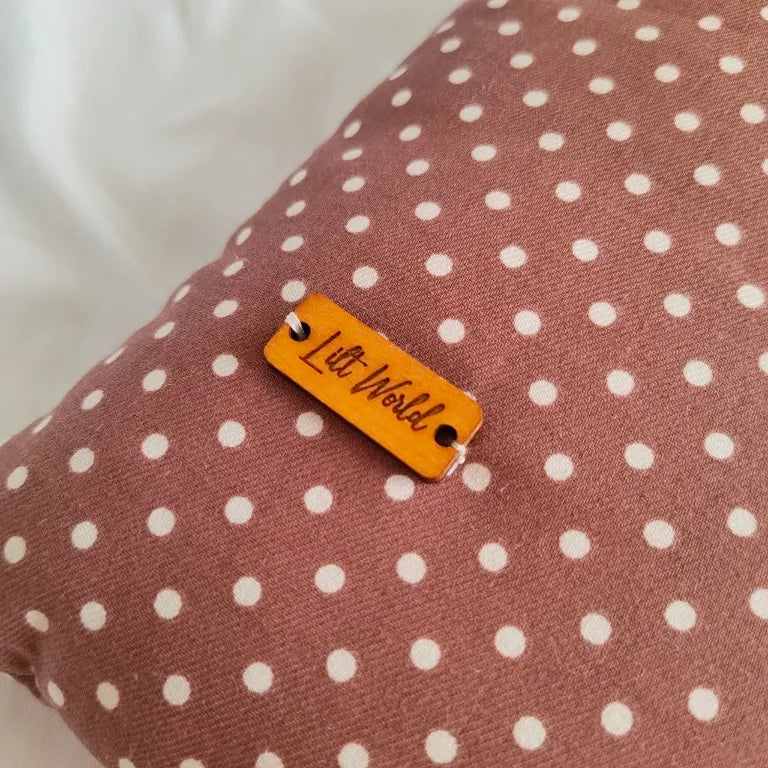Detalle de la chapa de madera con el logo de Lilt World cosida sobre la tela de lunares de la funda Moti.