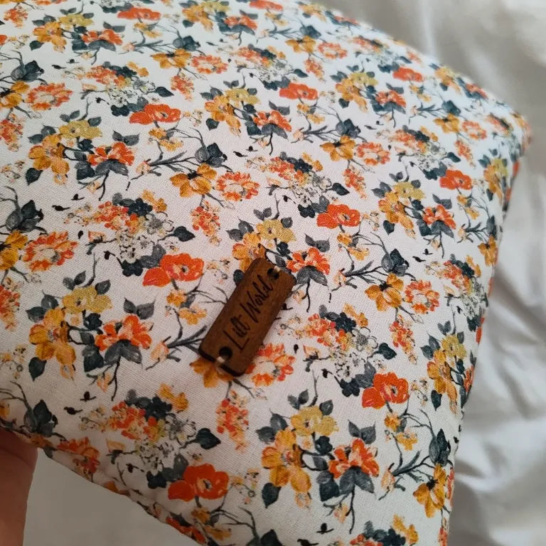 Primer plano del tejido floral estampado de la funda artesanal de tela con la etiqueta de madera de Lilt World.