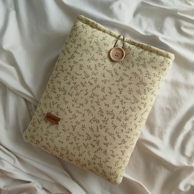 Vista frontal de la funda para libro y Kindle Jane con estampado de pequeñas ramas silvestres sobre fondo crema.