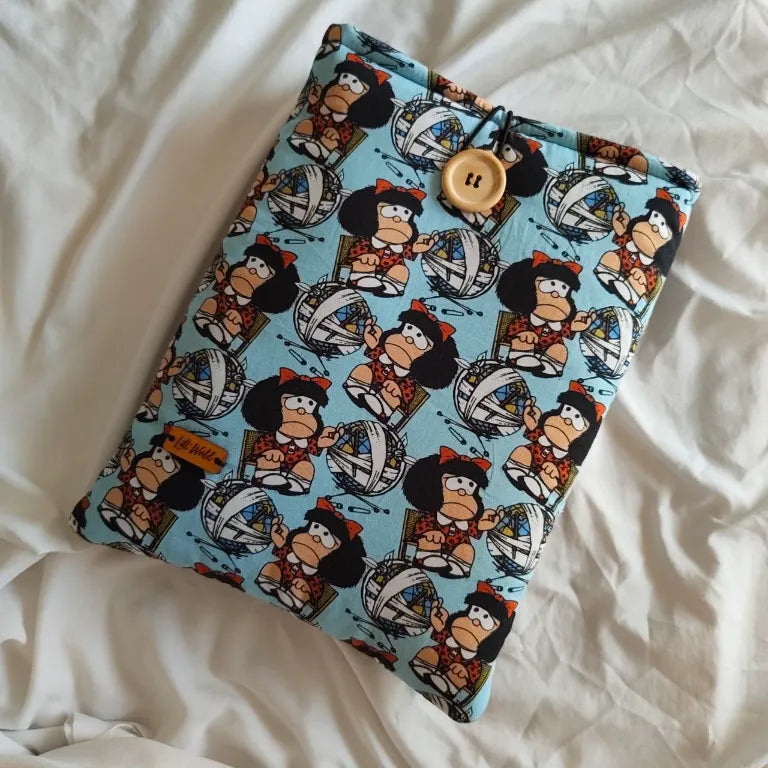 Vista frontal completa de la funda para libro y Kindle Quino con estampado de Mafalda y madejas de lana sobre fondo azul claro.
