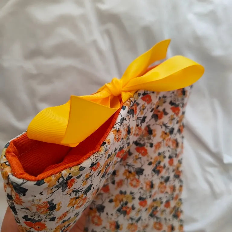 Detalle de la apertura superior de la funda para libros Solis mostrando el forro naranja y el lazo amarillo brillante.