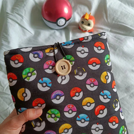  Funda de tela para libro y Kindle con diseño de Pokéballs de Pokémon en fondo negro.