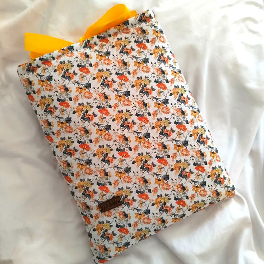 Funda acolchada para libros y Kindle Solis con estampado floral amarillo y naranja y cierre de lazo satinado.