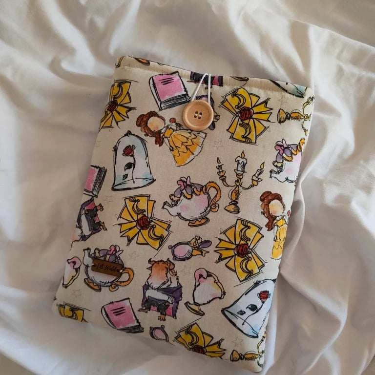 Vista completa de la funda protectora de libros con cierre de botón de madera elástico y estampado de la rosa encantada y la tetera.