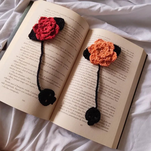 Pareja de marcapáginas de crochet Rosas Eternas en tono rojo y rosa claro colocados dentro de un libro abierto.