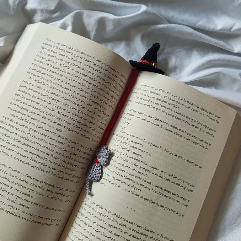 Marcapáginas de crochet Sombrero de Bruja desplegado sobre un libro abierto mostrando el sombrero y el gato gris