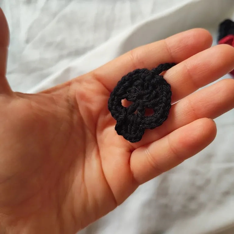 Detalle en la mano de la calavera negra amigurumi de crochet tejida a mano.