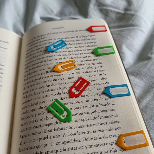 Marcadores de flecha reutilizables en varios colores sobre un libro, perfectos para estudiantes y lectores.
