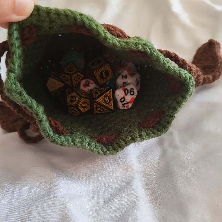 Vista superior del interior de la bolsa de dados verde de druida repleta de dados de rol para Dungeons & Dragons.