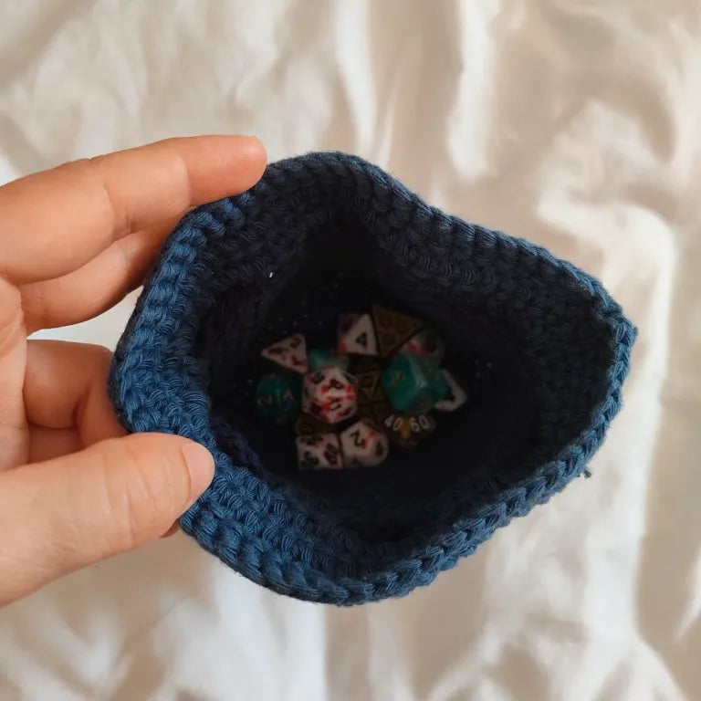 Interior de la bolsa para dados de crochet azul, repleta de dados de rol de resina y acrílico.